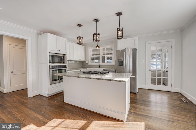 kitchen with a kitchen island, appliances with stainless steel finishes, white cabinetry, hanging light fixtures, and light stone countertops