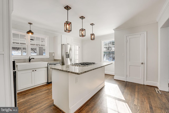 kitchen with sink, a center island, hanging light fixtures, appliances with stainless steel finishes, and white cabinets