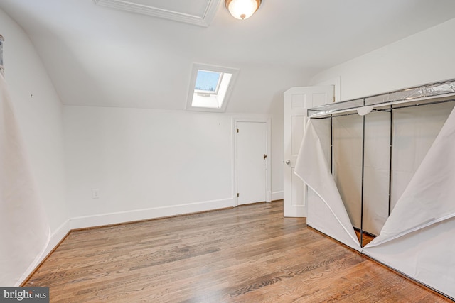 bonus room with vaulted ceiling with skylight and light hardwood / wood-style floors