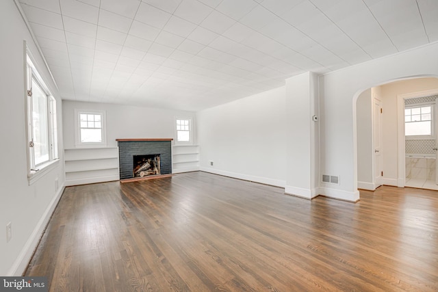 unfurnished living room featuring a fireplace, dark hardwood / wood-style flooring, and a wealth of natural light