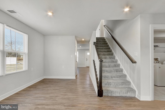 stairway with hardwood / wood-style flooring and washer / dryer