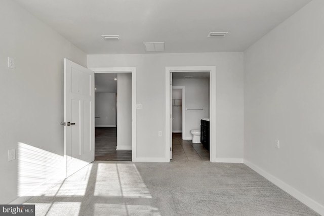 unfurnished bedroom featuring a walk in closet, carpet flooring, and connected bathroom