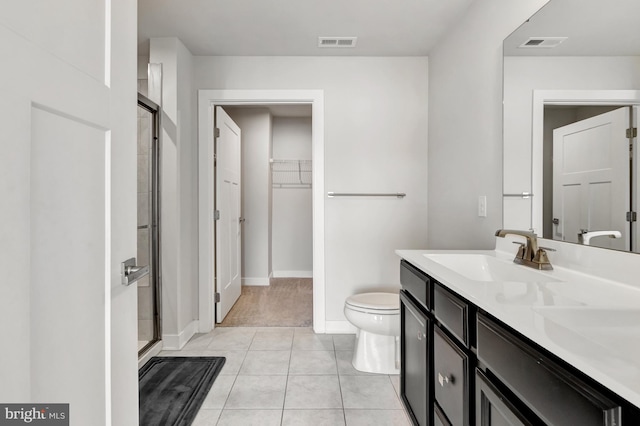 bathroom with toilet, vanity, a shower with door, and tile patterned flooring