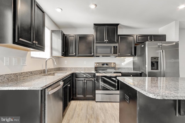 kitchen with sink, light hardwood / wood-style flooring, light stone countertops, and appliances with stainless steel finishes