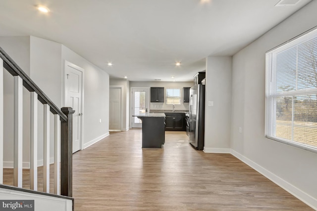 kitchen featuring stainless steel refrigerator, a center island, sink, and light wood-type flooring