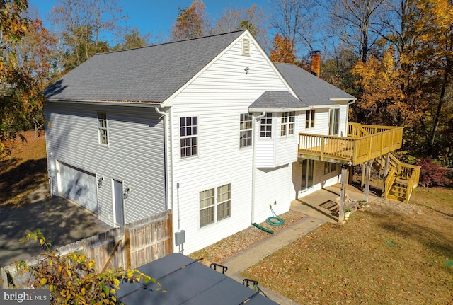 rear view of property with a garage and a deck