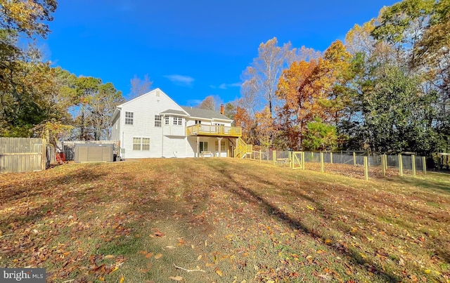 back of property with a deck, a lawn, and a hot tub