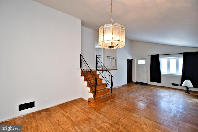 foyer featuring an inviting chandelier, hardwood / wood-style floors, and vaulted ceiling