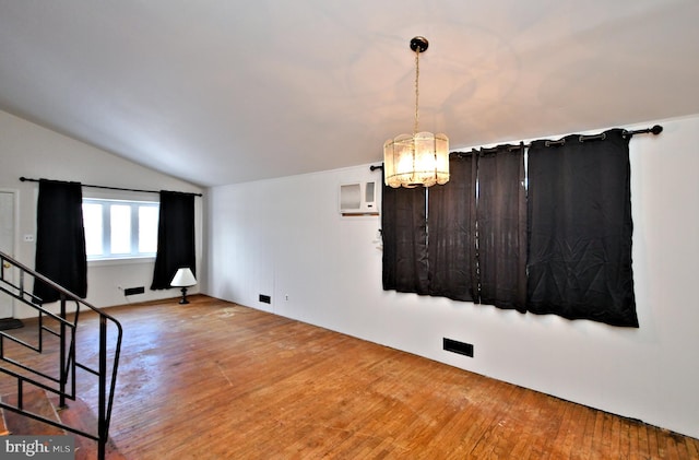 interior space featuring lofted ceiling, hardwood / wood-style floors, an AC wall unit, and a chandelier