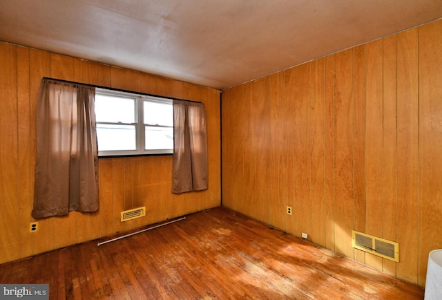 spare room with wood-type flooring and wood walls