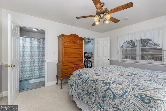 bedroom with a spacious closet, light carpet, ceiling fan, and a closet