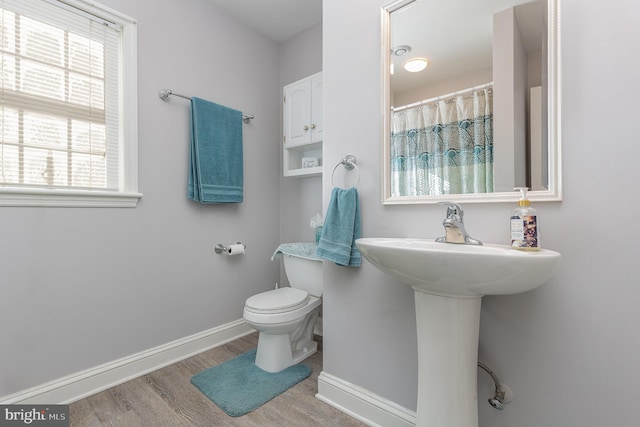 bathroom featuring curtained shower, wood-type flooring, and toilet