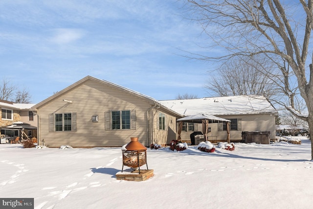 snow covered house featuring a hot tub