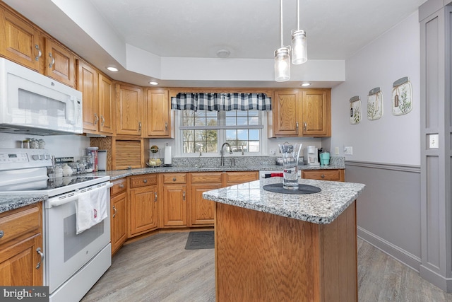 kitchen with white appliances, sink, a kitchen island, and light wood-type flooring