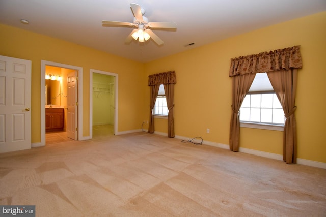 empty room featuring ceiling fan, plenty of natural light, and light carpet