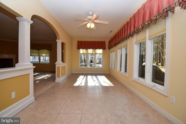 hallway with light tile patterned floors, plenty of natural light, and ornate columns