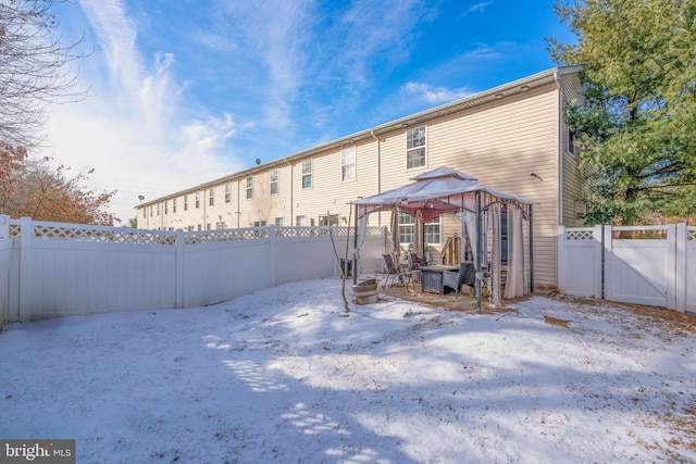 snow covered back of property with a gazebo