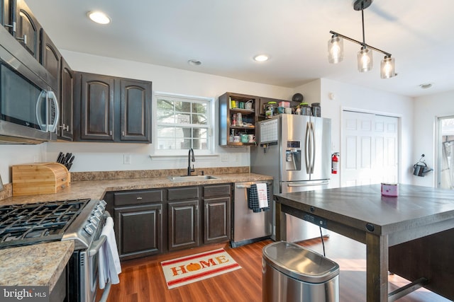 kitchen with hanging light fixtures, sink, dark brown cabinets, dark hardwood / wood-style flooring, and stainless steel appliances