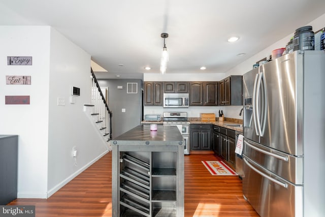 kitchen featuring pendant lighting, appliances with stainless steel finishes, dark hardwood / wood-style flooring, and dark brown cabinets