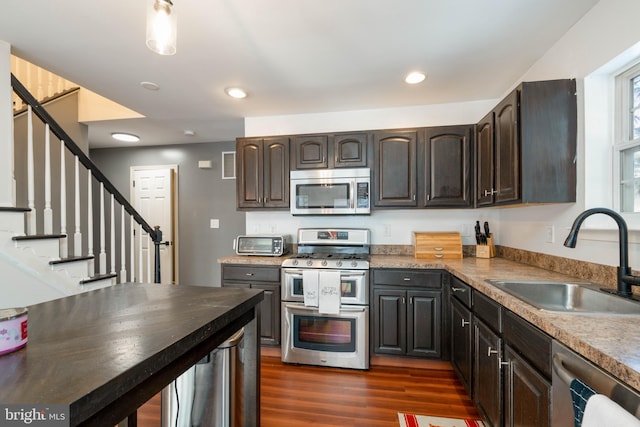 kitchen with sink, dark brown cabinets, appliances with stainless steel finishes, and dark hardwood / wood-style flooring