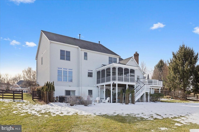 snow covered property featuring a lawn, a sunroom, and a deck