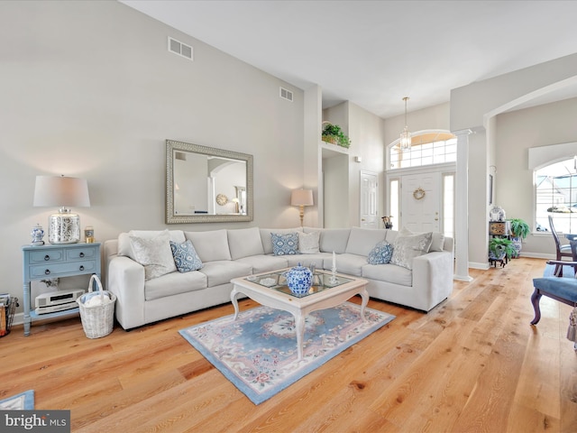 living room featuring a healthy amount of sunlight, light hardwood / wood-style flooring, and ornate columns