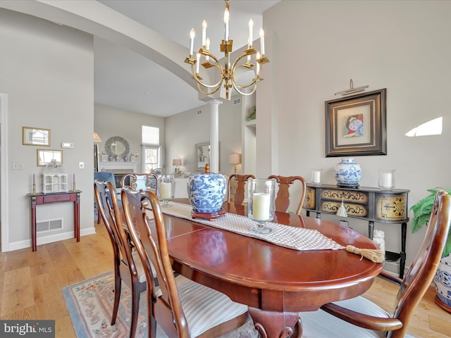 dining room with decorative columns, a chandelier, and light wood-type flooring