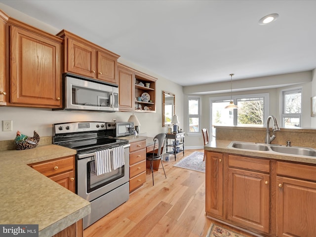 kitchen with sink, decorative light fixtures, stainless steel appliances, and light hardwood / wood-style floors