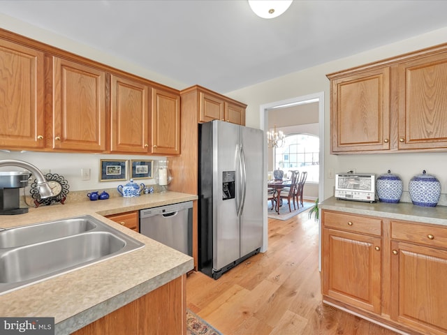 kitchen featuring stainless steel appliances, a chandelier, sink, and light hardwood / wood-style flooring