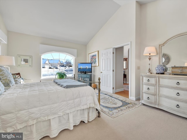 bedroom with high vaulted ceiling and light carpet