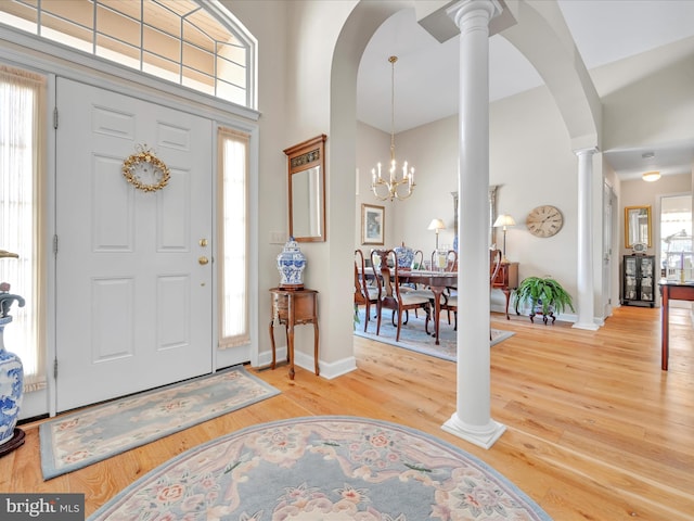 entrance foyer with a notable chandelier, wood-type flooring, a high ceiling, and ornate columns