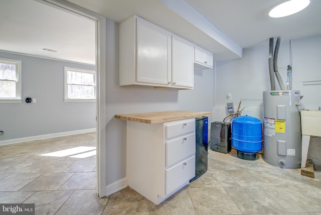 interior space with white cabinetry, electric water heater, sink, and wooden counters