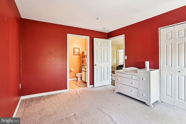 bedroom featuring a closet, connected bathroom, and light carpet