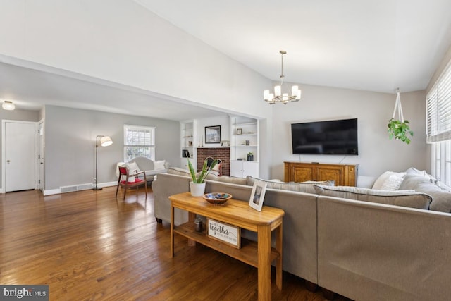 living room with an inviting chandelier, a fireplace, visible vents, lofted ceiling, and wood finished floors