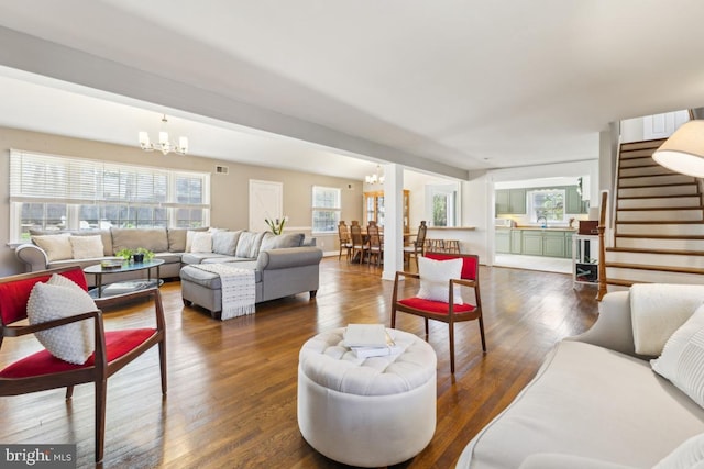 living area featuring stairway, a notable chandelier, and wood finished floors