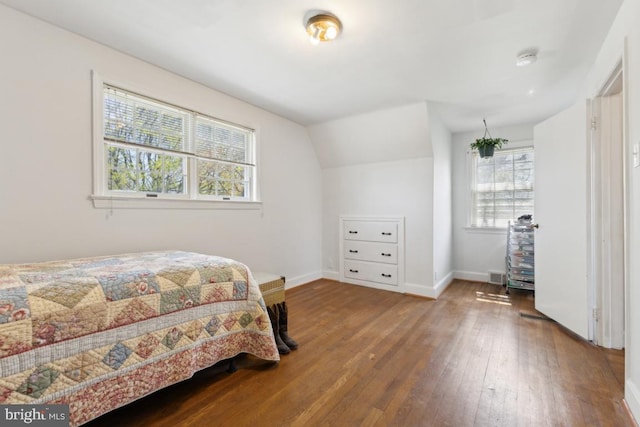 bedroom featuring visible vents, baseboards, hardwood / wood-style flooring, and lofted ceiling