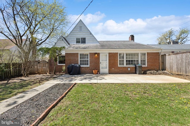 back of house featuring brick siding, a fenced backyard, a patio, and a lawn