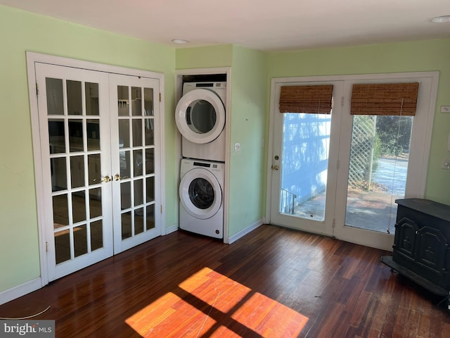 washroom with stacked washer / dryer, a wood stove, dark wood-type flooring, and french doors