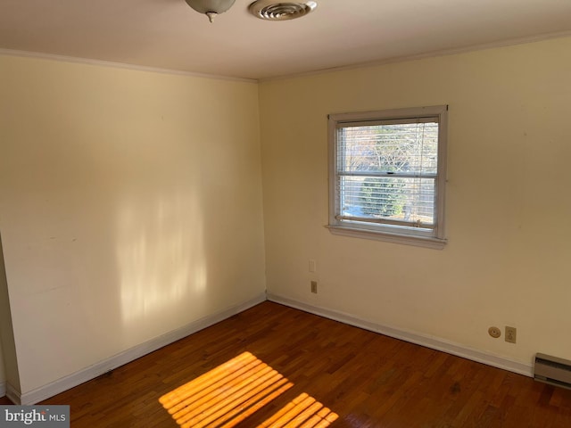 empty room with ornamental molding, dark hardwood / wood-style floors, and baseboard heating