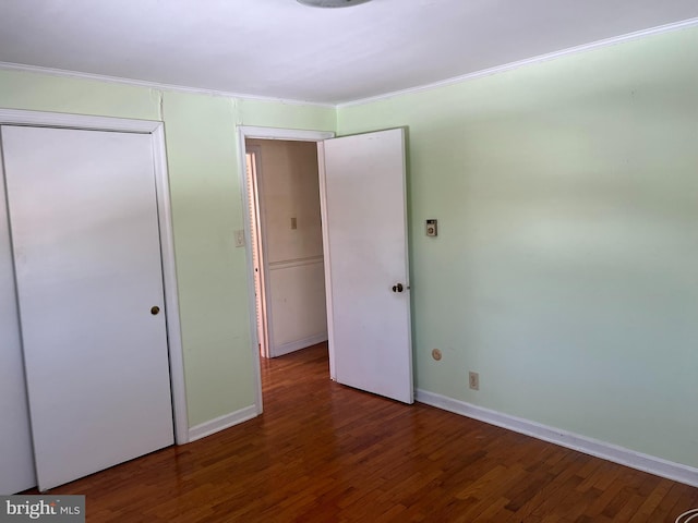 unfurnished bedroom featuring ornamental molding, dark wood-type flooring, and a closet