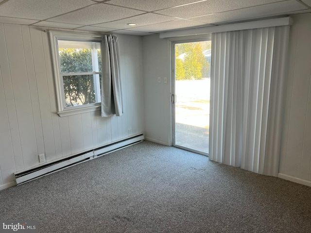 carpeted empty room with a paneled ceiling and baseboard heating