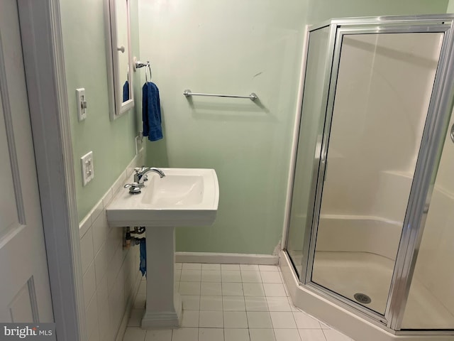 bathroom with an enclosed shower, sink, and tile patterned floors