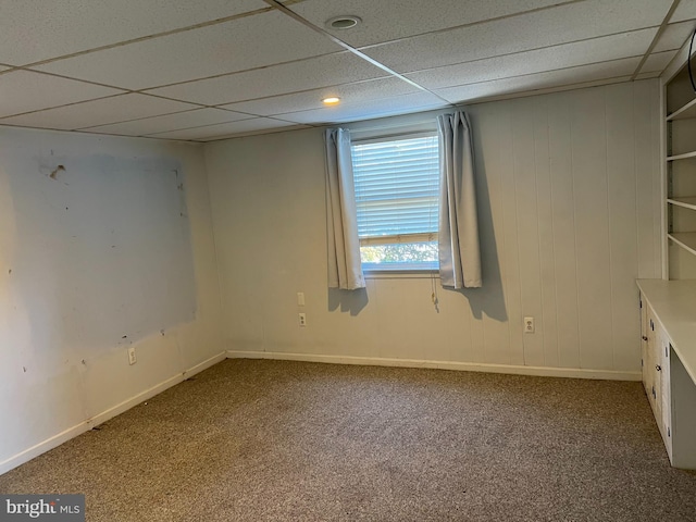 carpeted empty room featuring a drop ceiling