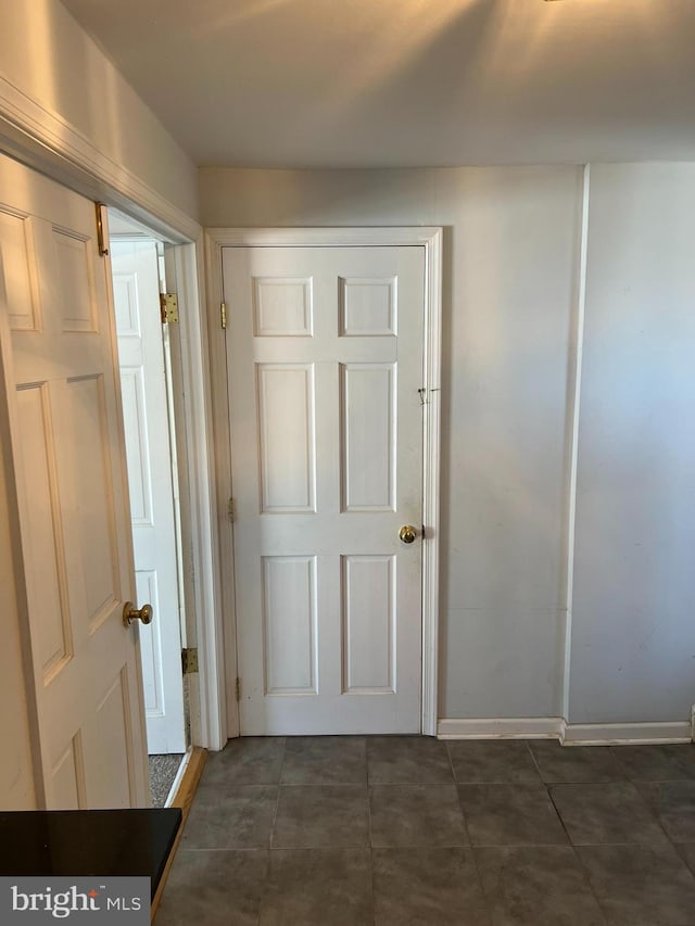 hall featuring dark tile patterned flooring