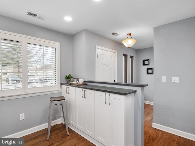 kitchen with white cabinetry, dark hardwood / wood-style floors, decorative light fixtures, and kitchen peninsula