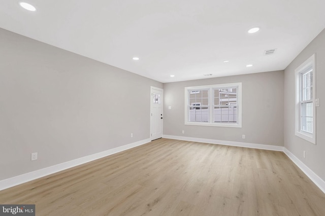 empty room with plenty of natural light and light hardwood / wood-style flooring