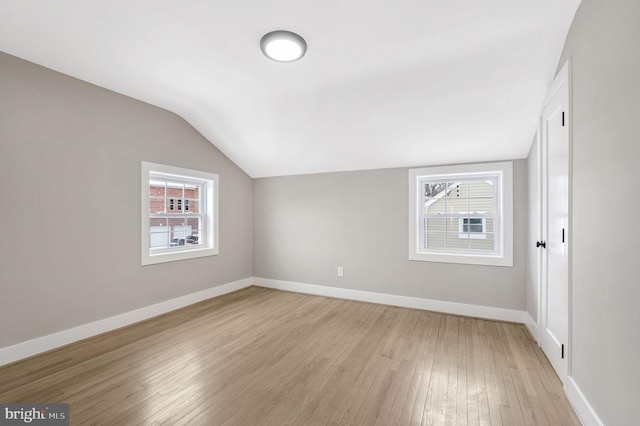 additional living space with light hardwood / wood-style flooring and vaulted ceiling