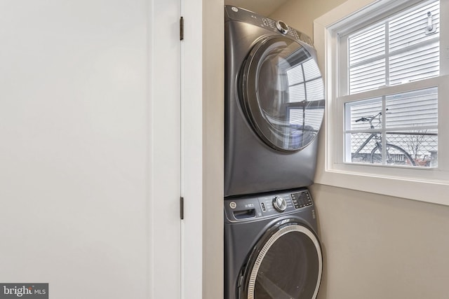 clothes washing area featuring plenty of natural light and stacked washing maching and dryer