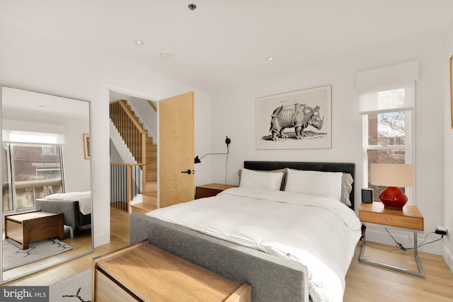 bedroom with light hardwood / wood-style floors and multiple windows