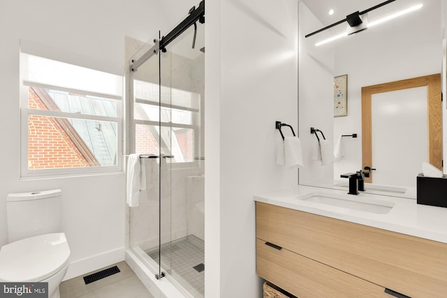 bathroom featuring walk in shower, vanity, toilet, and tile patterned flooring